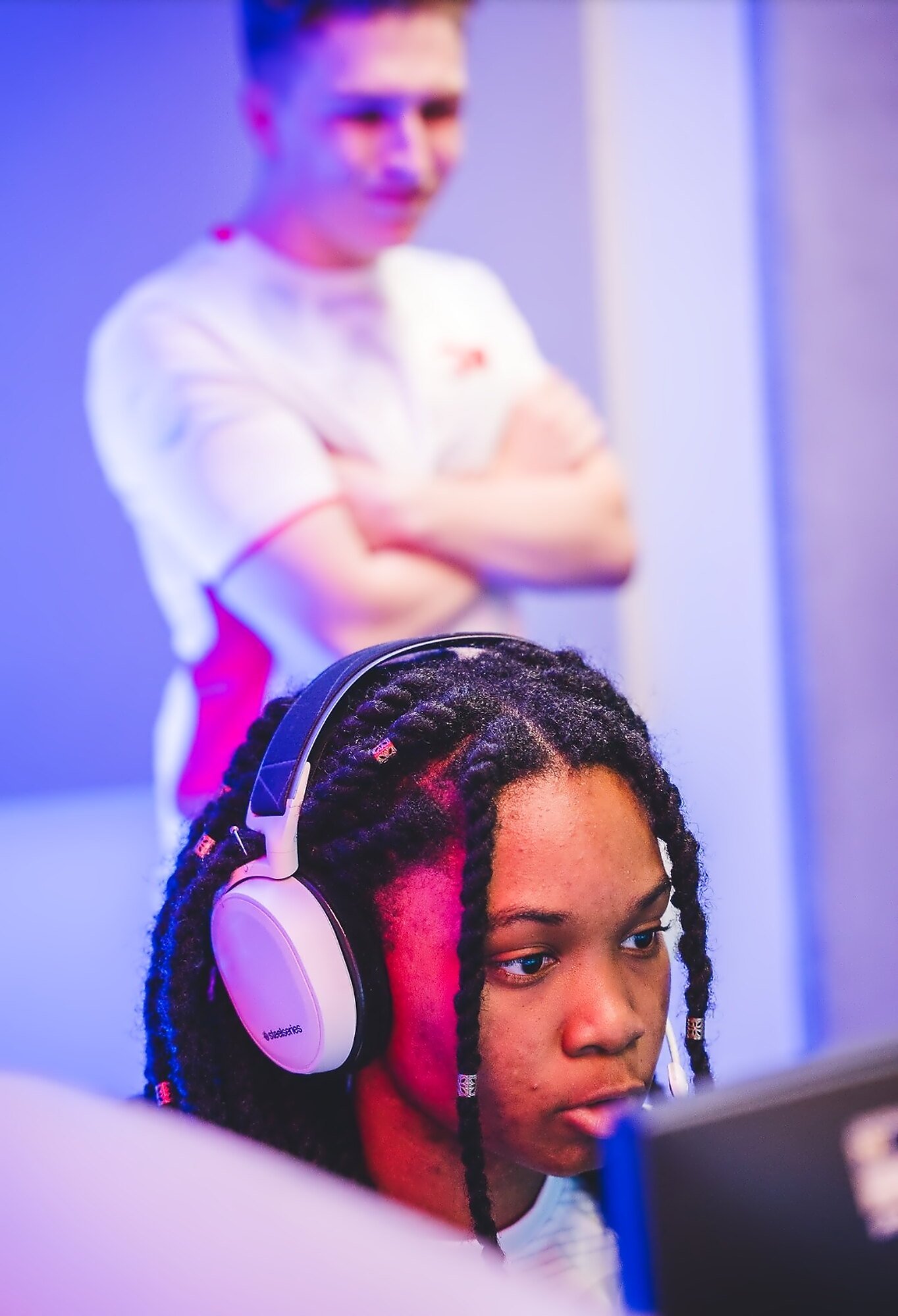 Alanis concentrating at her PC while a Team England teammate looks on